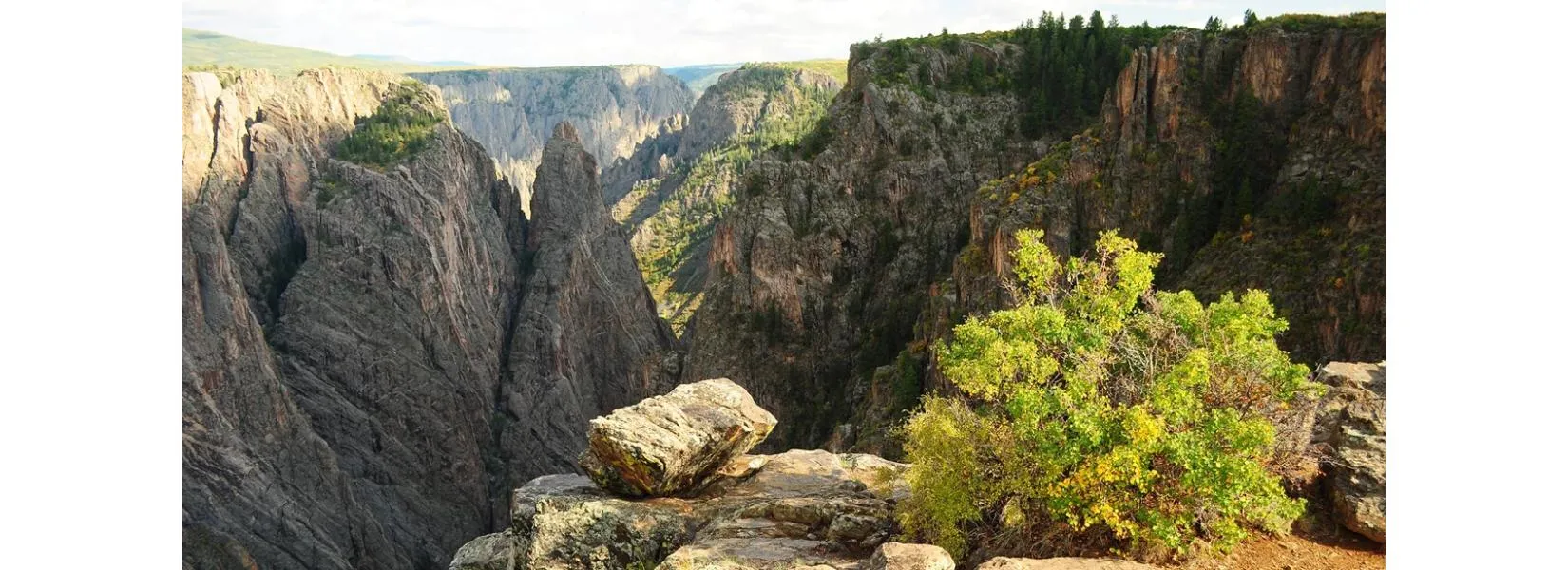 Spectacular view into Black Canyon from Cross Fissures Overlook showing the deep canyon walls and dramatic rock formations that await visitors following directions to Black Canyon of the Gunnison
